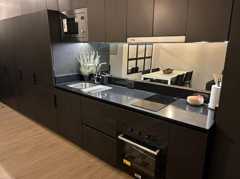 a kitchen with black cabinets and a sink at Estudio en Estoril cercano a principales centros de ski in Santiago