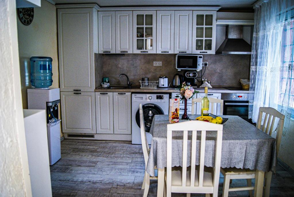 eine Küche mit einem Tisch und Stühlen sowie eine Küche mit weißen Schränken in der Unterkunft NIKI Apart in Sofia