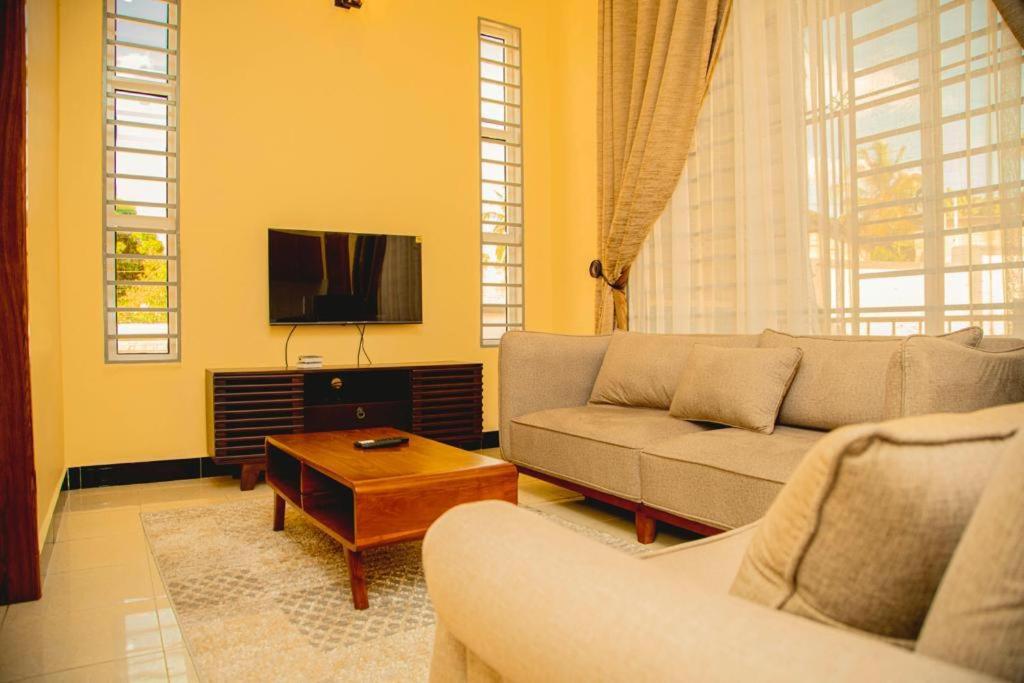 a living room with a couch and a tv at Nellly's Rest House in Dar es Salaam