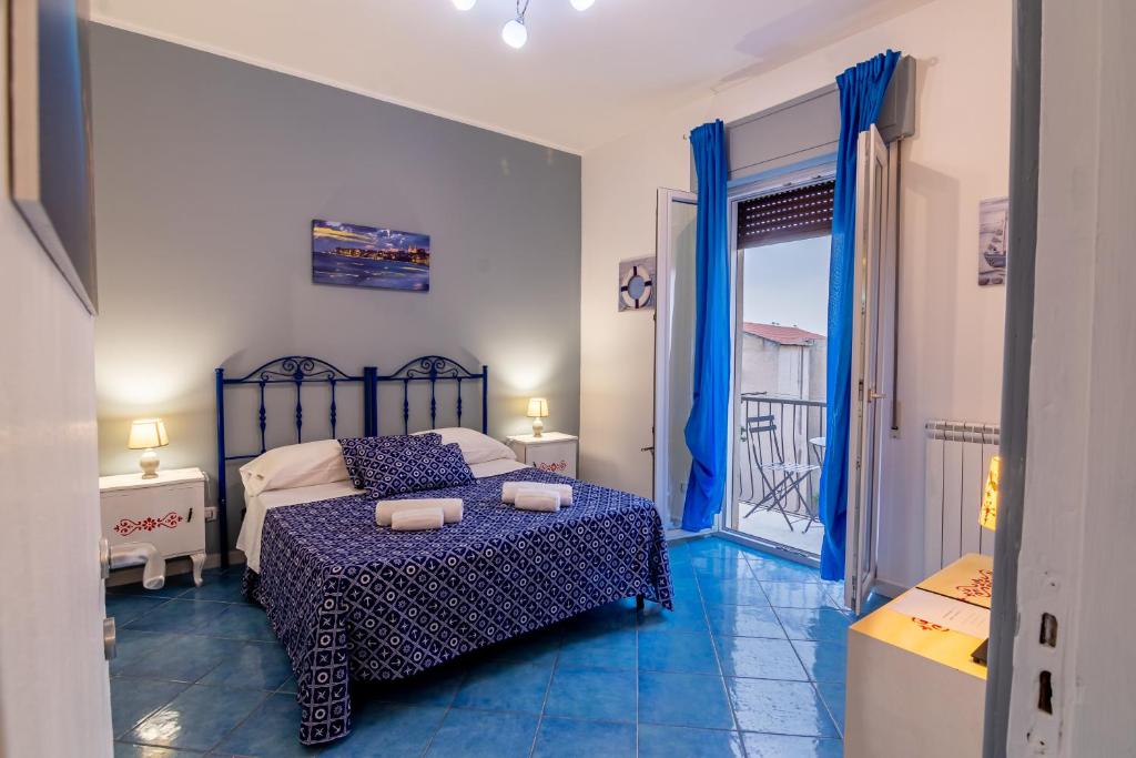 um quarto com uma cama com um edredão azul em ARIA DI MARE ROOMS em Cefalù