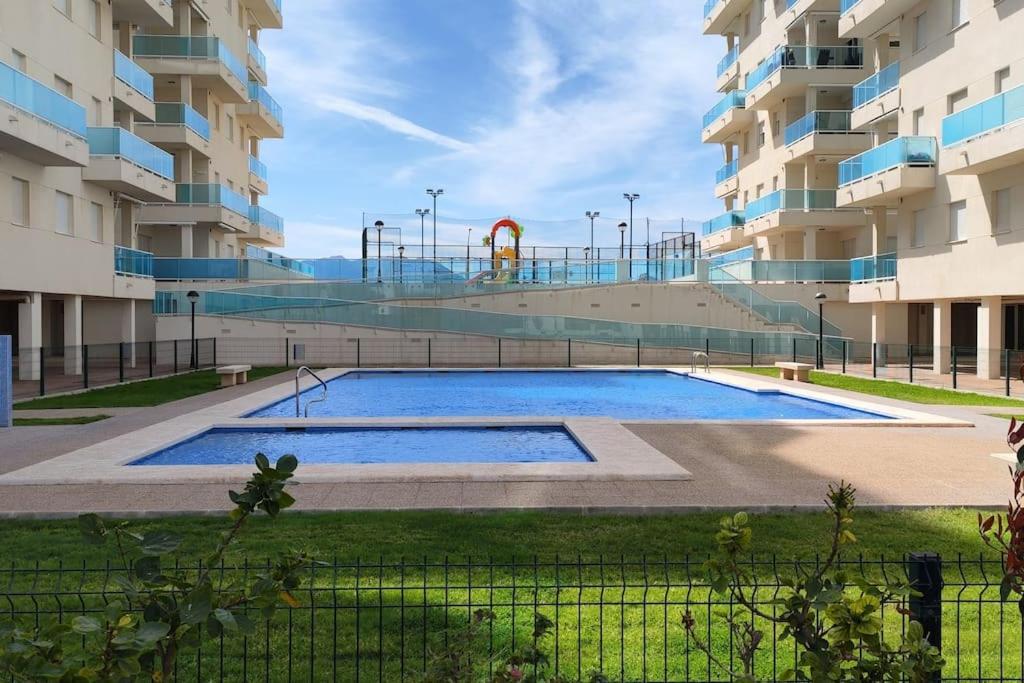 - une piscine en face d'un bâtiment avec une aire de jeux dans l'établissement Apartamento nuevo en playa de Piles. Costa Blanca, à Piles