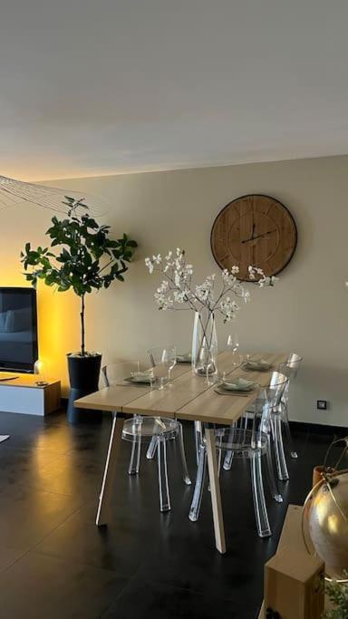 une salle à manger avec une table, des chaises et une horloge dans l'établissement Logement accès JO avec Jardin et Jacuzzi, à Bussy-Saint-Georges