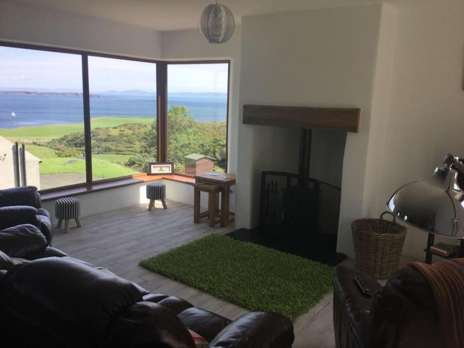 a living room with a couch and a large window at Kinbane Self Catering Cottages - 'Makem's Cottage' in Ballycastle