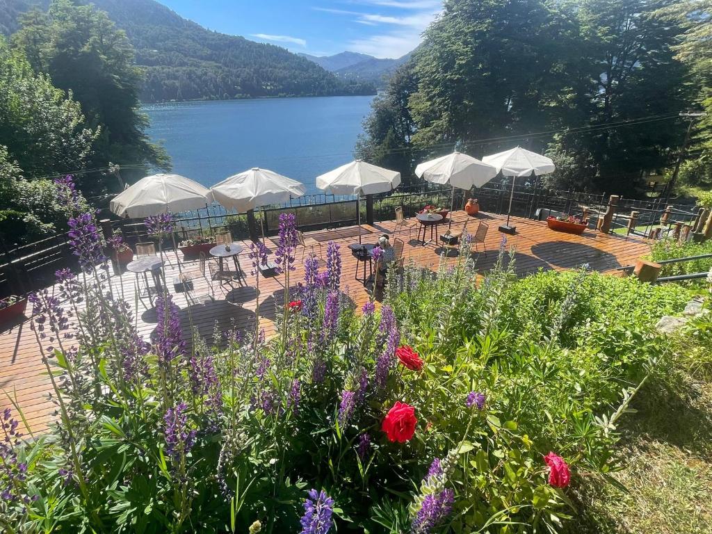 kilka stołów i białych parasoli obok jeziora w obiekcie Hosteria El Condado by Nordic w mieście Bariloche