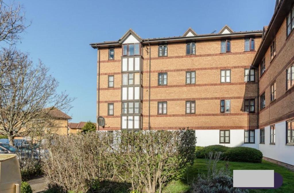 un grande edificio in mattoni con alberi di fronte di Frobisher Apartment a Erith