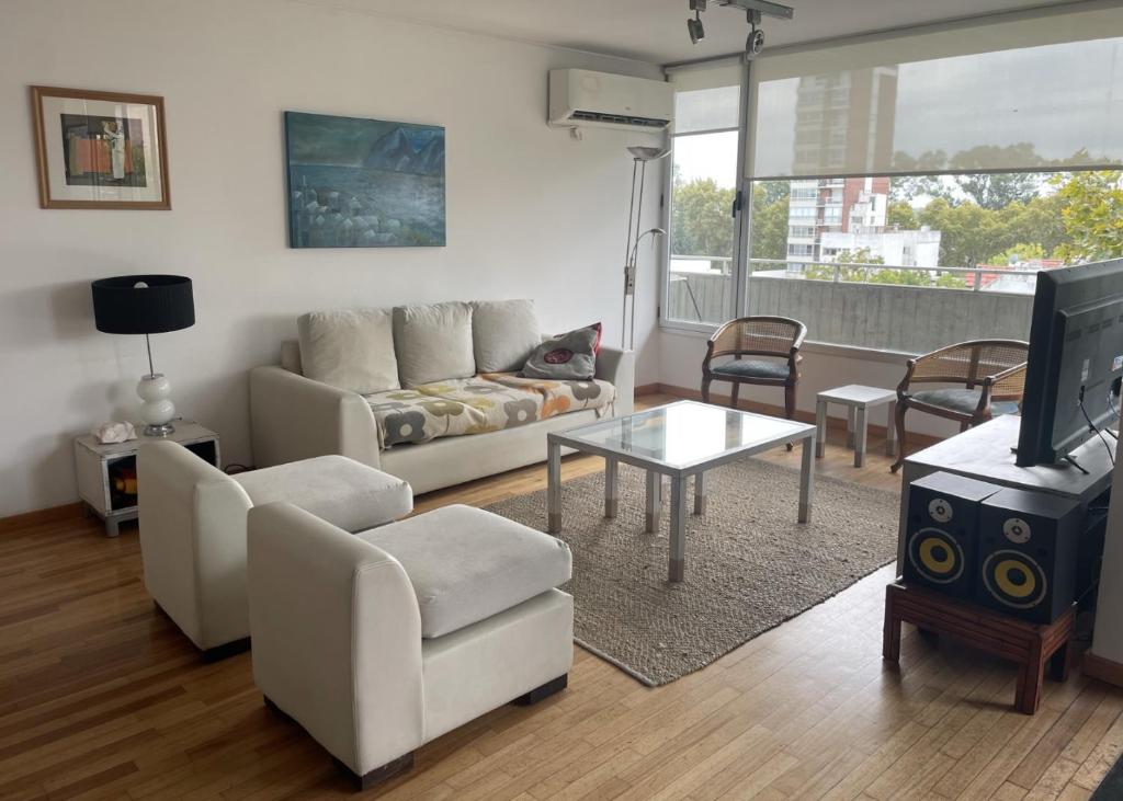 a living room with a couch and a tv at Pichincha Guemes Balcon in Rosario