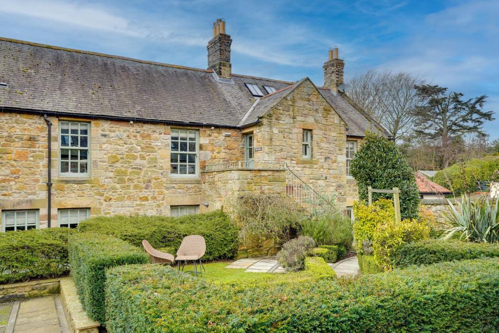 an old stone house with a garden in front of it at Pope Lodge: Stunning Stone Coach House Conversion in Alnmouth