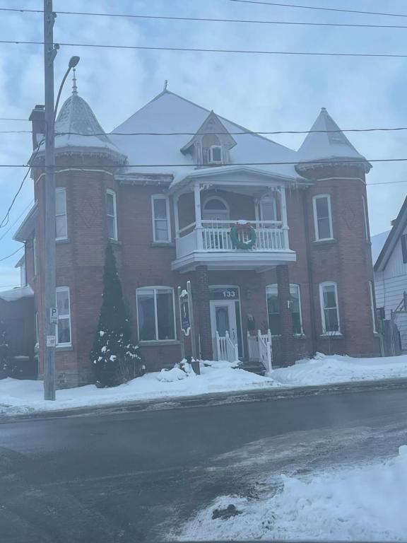 a large red brick house with a white balcony at AUBERGE et BISTRO NAMASTÉ in Lachute