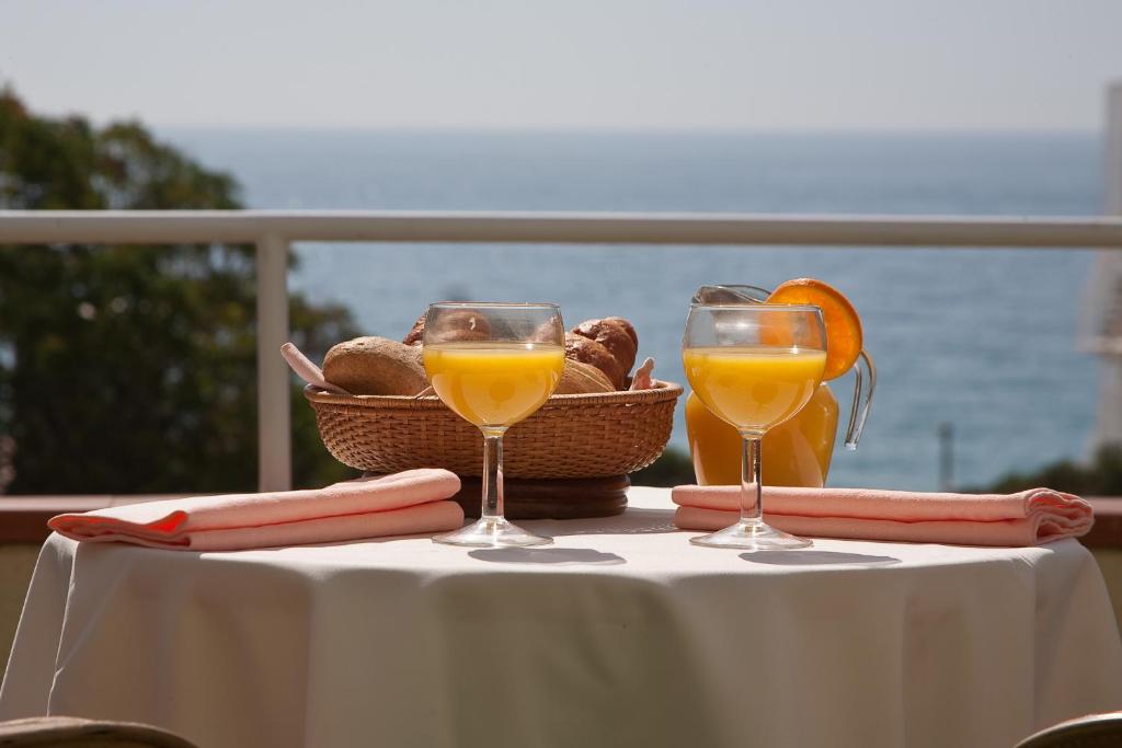 a table with two glasses of orange juice and a basket of bread at Hotel Claramar in Platja d'Aro