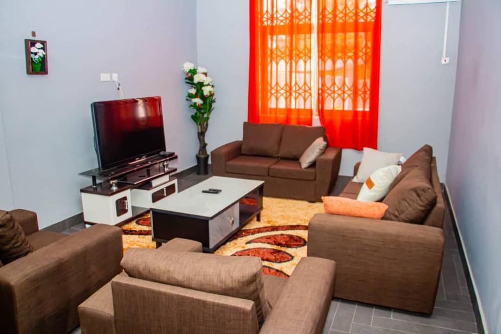 Il comprend un salon avec des canapés et une télévision à écran plat. dans l'établissement Accra cosy homes near beaches and mall, à Accra