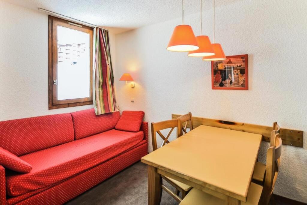 un salon avec un canapé rouge et une table dans l'établissement Résidence Les Chalets des Arolles - maeva Home - Studio 4 Personnes - Confort MAE-8704, à La Plagne Tarentaise