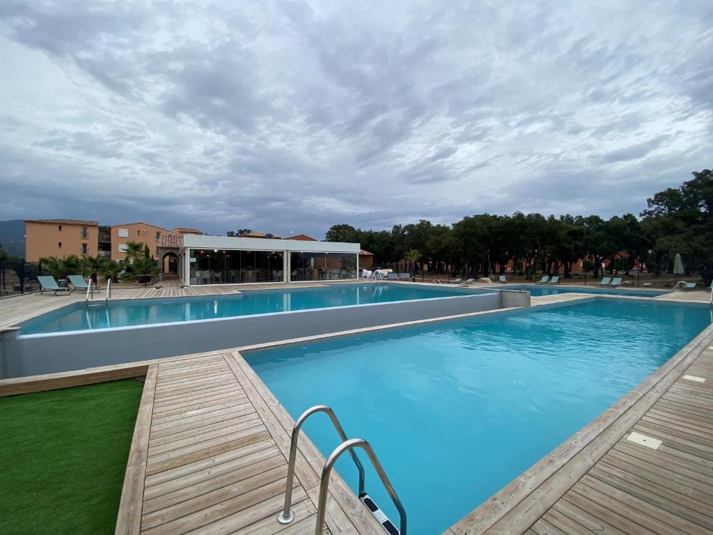 uma grande piscina com um deque de madeira em Appartement 2 pièces dans une résidence hôtelière Les Hameaux de Saint-Cyprien em Lecci