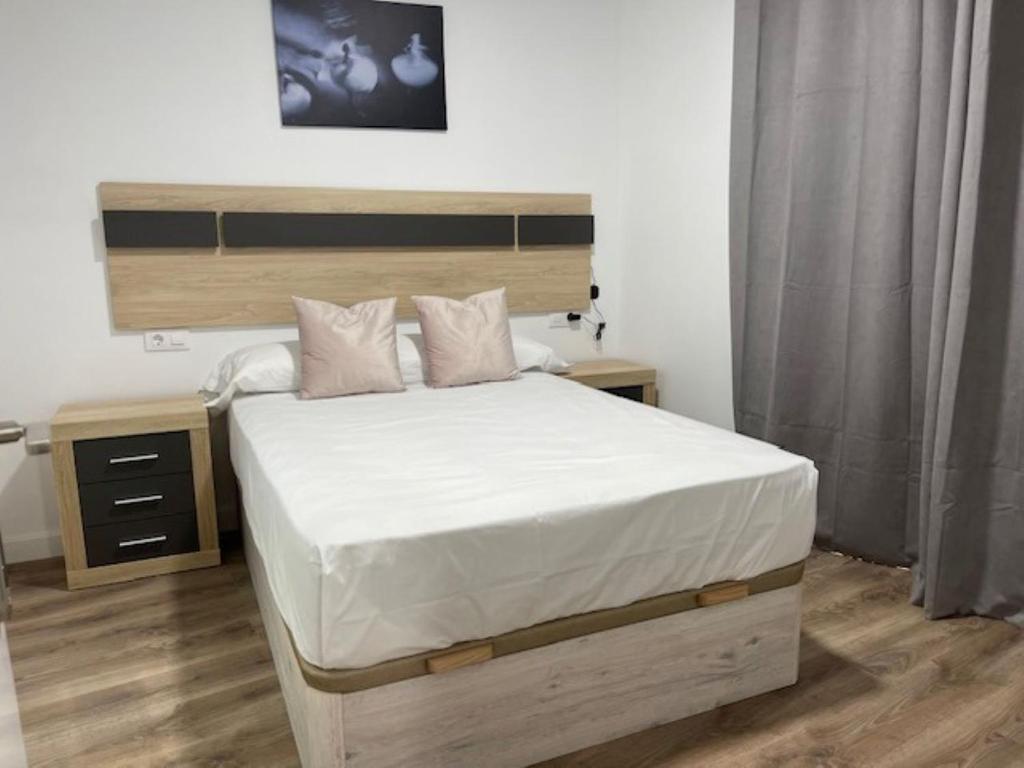 a bedroom with a large bed with a wooden headboard at Apartamento Torre del Castillo in Sanlúcar de Barrameda