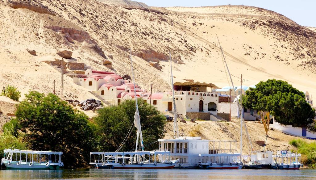 a group of boats in the water near a building at Hadouta Masreya Nubian Guest House in Aswan
