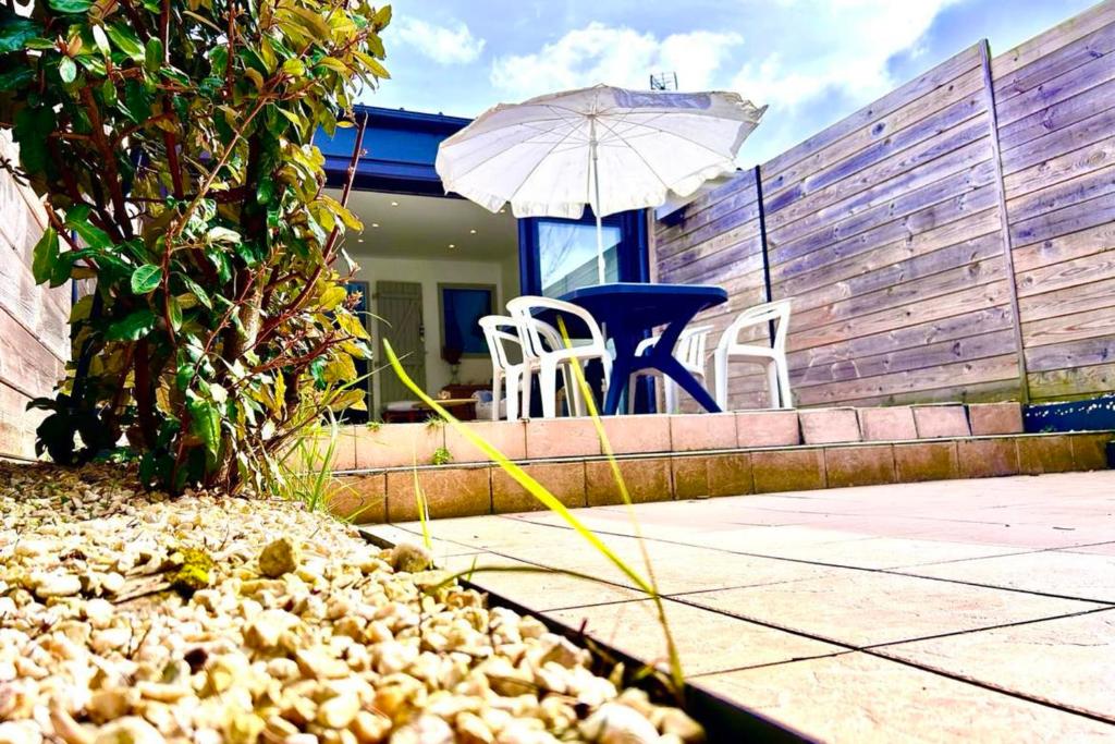 a patio with a table and chairs and an umbrella at Bright house with terrace and garden in Camiers