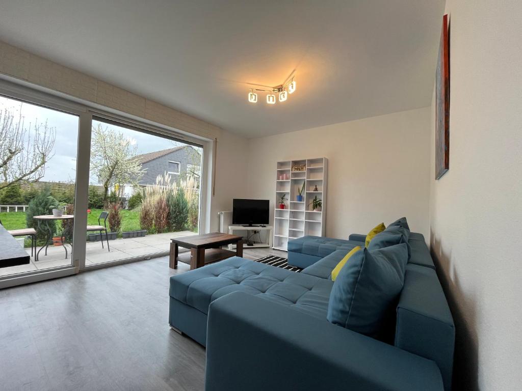 a living room with a blue couch and a large window at Serene Meadows Apartment in Solingen