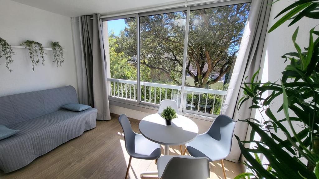 ein Wohnzimmer mit einem Tisch und Stühlen sowie einem großen Fenster in der Unterkunft Appartement de 50 m2 cosy et moderne à 100 m de la plage in Saint-Mandrier-sur-Mer