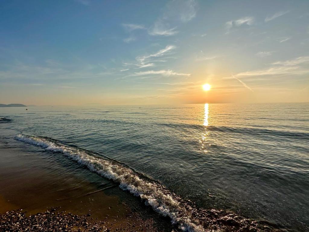a beach with the sun rising over the ocean w obiekcie Stella di Mare - 20 mt dalla spiaggia w mieście San Vincenzo