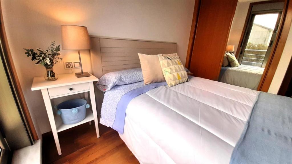 a bedroom with a bed and a table with a lamp at Apartamento-Suite Playa en San Antón in Porto de Espasante