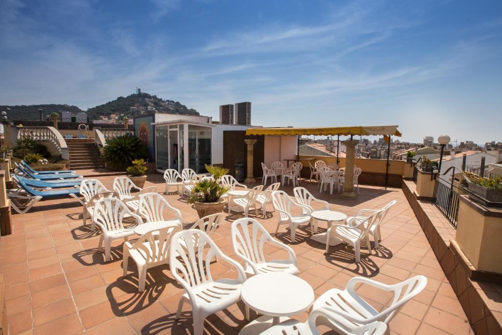 a patio with white chairs and tables on a roof at Hotel Costa Brava in Blanes