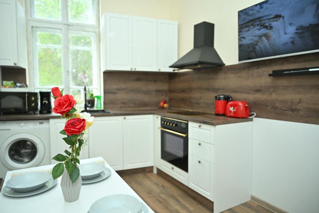 a white kitchen with a vase of roses on a table at Апартамент в топ центъра на Велико Търново in Veliko Tŭrnovo