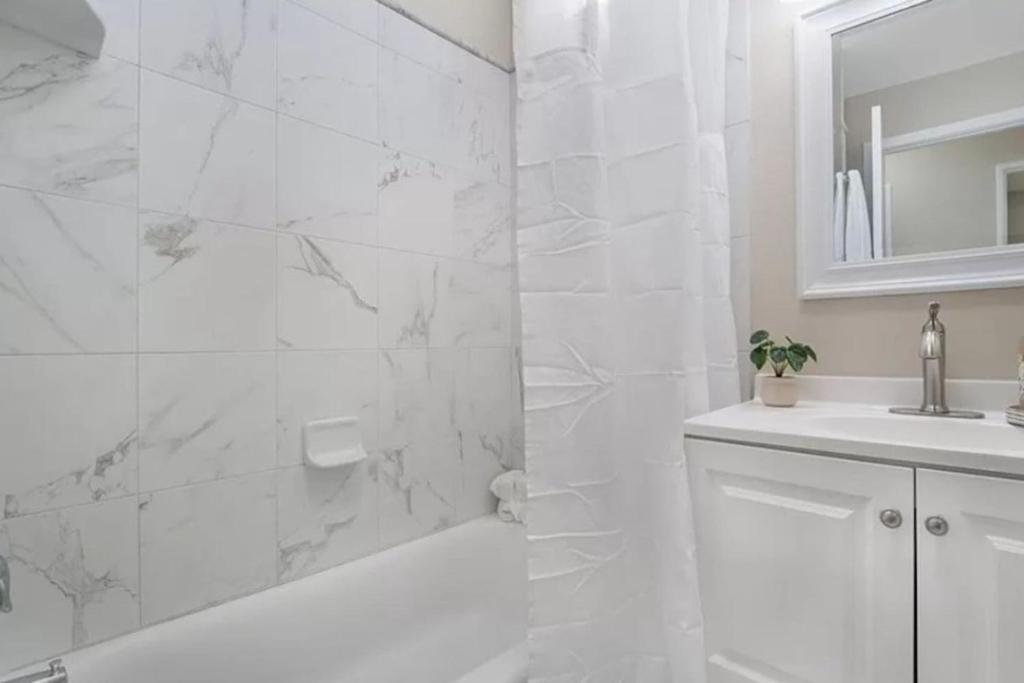 a white bathroom with a tub and a sink at Modern Home Near Ontario Airport in Ontario