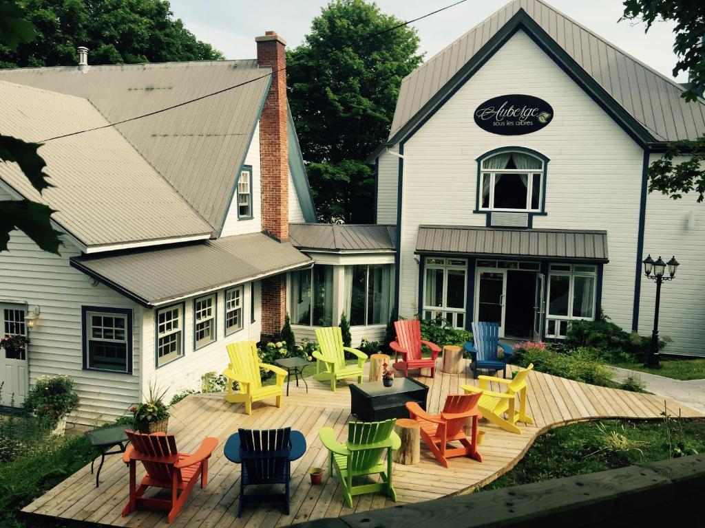 a deck with colorful chairs and tables in front of a building at Auberge Sous les Arbres in Gaspé