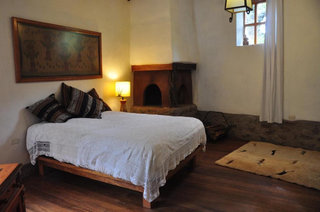 1 dormitorio con 1 cama y chimenea en Valle Dorado Lodge, en Cusco