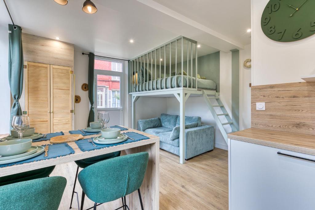 a kitchen and living room with a dining table and a bunk bed at L'olivier Studio Lumineux avec agréable terrasse in Fécamp