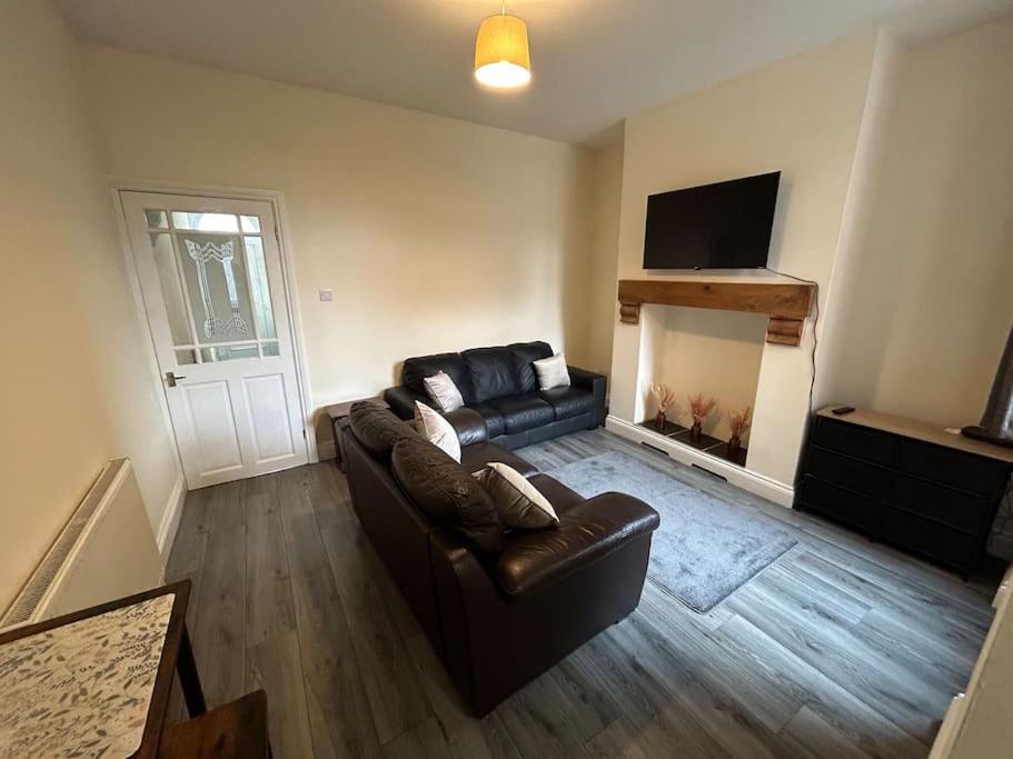 a living room with a leather couch and a fireplace at 3 Bedroom Home From Home, Crewe in Crewe