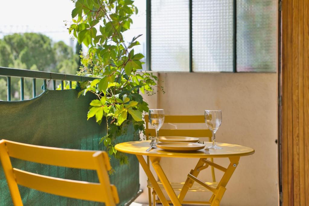 une table et des chaises jaunes avec des verres à vin dans l'établissement Charming apartment with balcony and panoramic view, à Aix-en-Provence