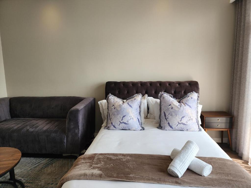 a bedroom with a bed and a leather couch at The Trilogy Penthouse 1603 in Pretoria