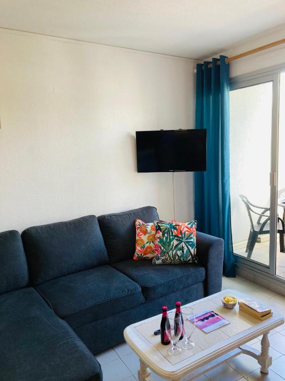 un salon avec un canapé bleu et une table dans l'établissement Bienvenue chez Méli et Dorian, à La Grande Motte