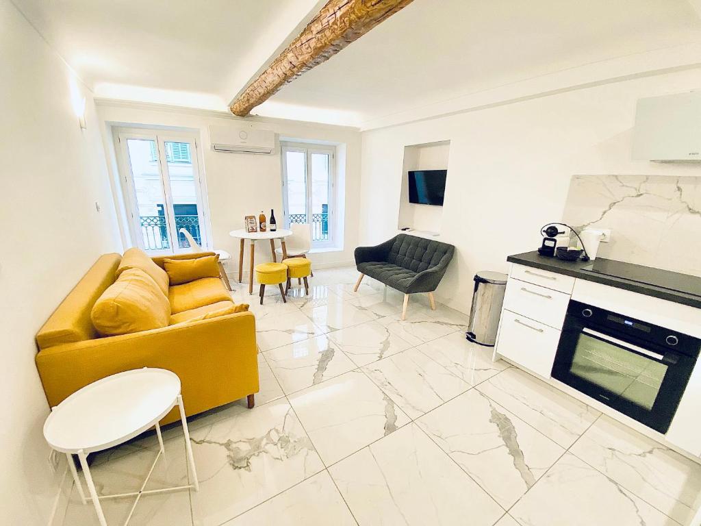 ein Wohnzimmer mit einem gelben Sofa und einer Küche in der Unterkunft T3 carré d’or plein centre in Nizza