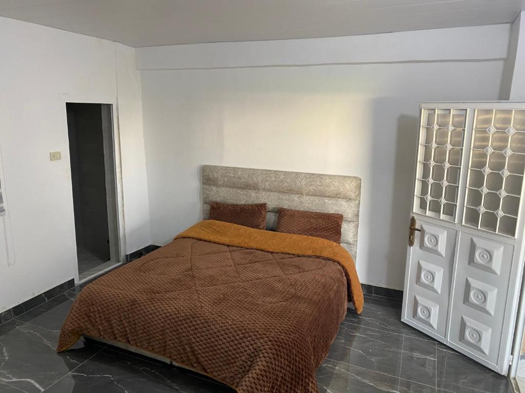 um quarto com uma cama com um cobertor laranja em huseein rooms em Gérasa
