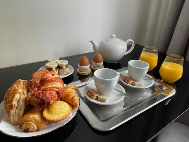 a tray of croissants and eggs on a table at Grand appartement d'exception au Château Randin in Écully
