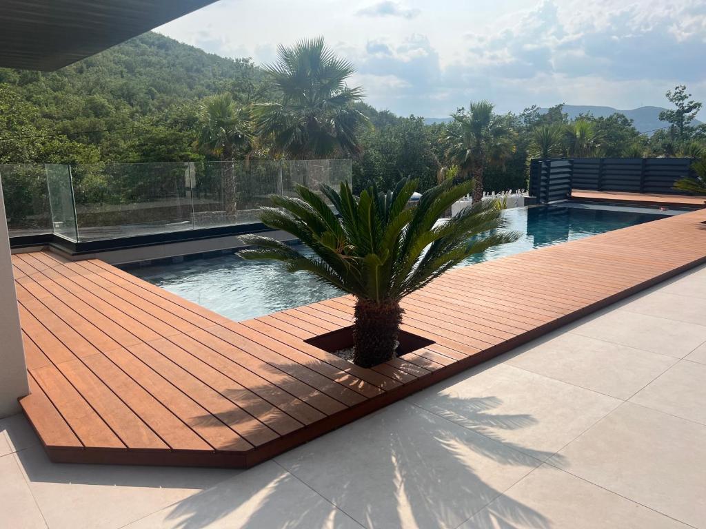 - une piscine avec un palmier sur une terrasse en bois dans l'établissement Logement avec piscine paradisiaque, aux Tourrettes