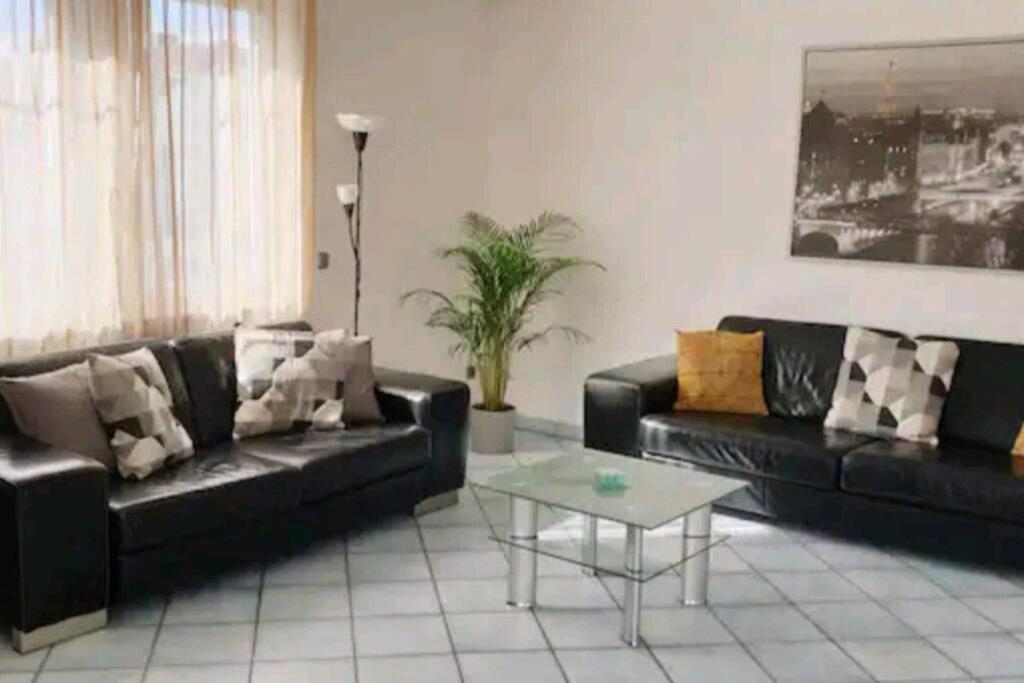 a living room with two black couches and a coffee table at Spacious 100sq m apartment in Tuchenbach