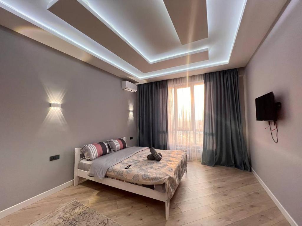 um quarto com uma cama e uma grande janela em ЖК Terracotta em Almaty
