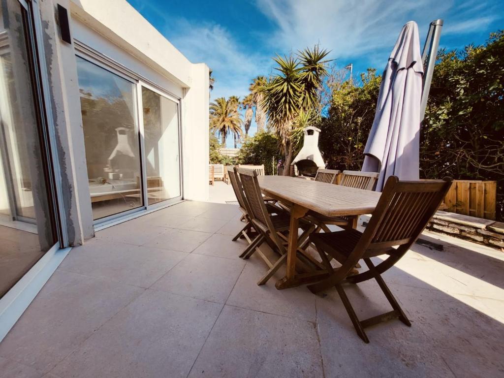 a table and chairs on a patio with an umbrella at VILLA BORD DE MER 6 COUCHAGES AVEC JARDIN ET GARAGE in La Grande-Motte