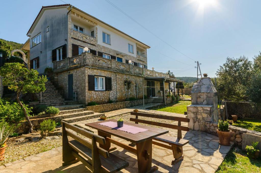 a table and benches in front of a house at Apartments Mrvelj in Gdinj