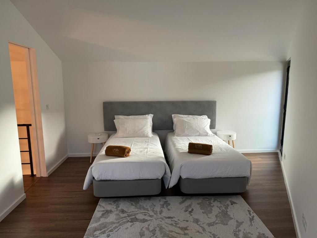 2 łóżka w pokoju z białymi ścianami i drewnianą podłogą w obiekcie Oak Retreat House w mieście Lagoa