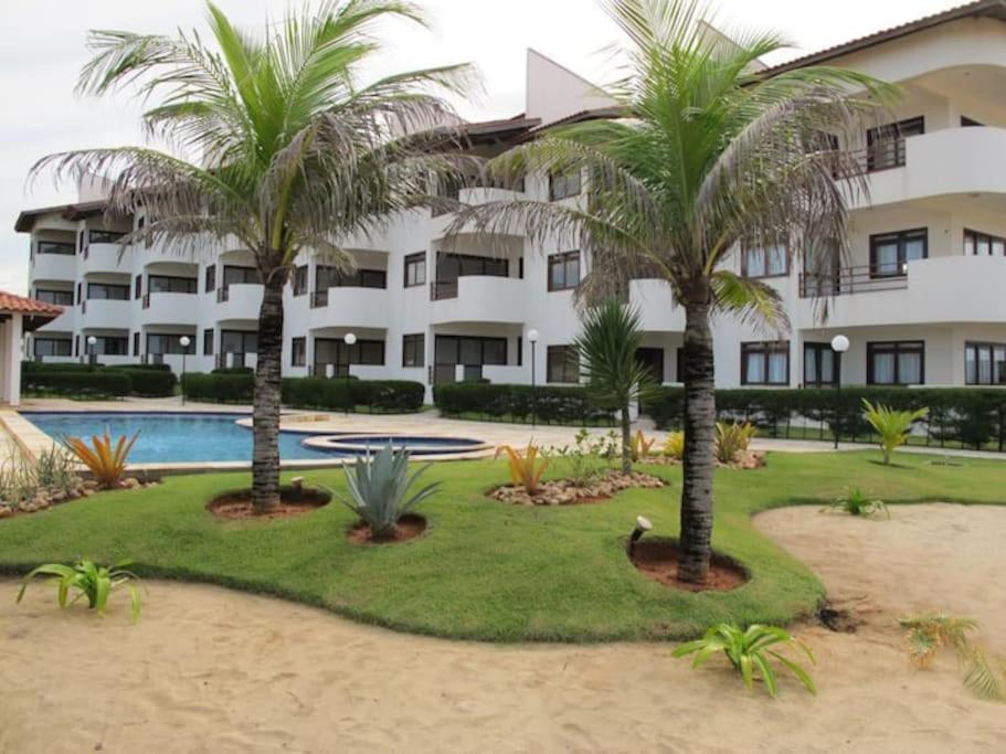 a resort with palm trees and a swimming pool at Apartamento à beira-mar. Beachfront apartment in São Gonçalo do Amarante