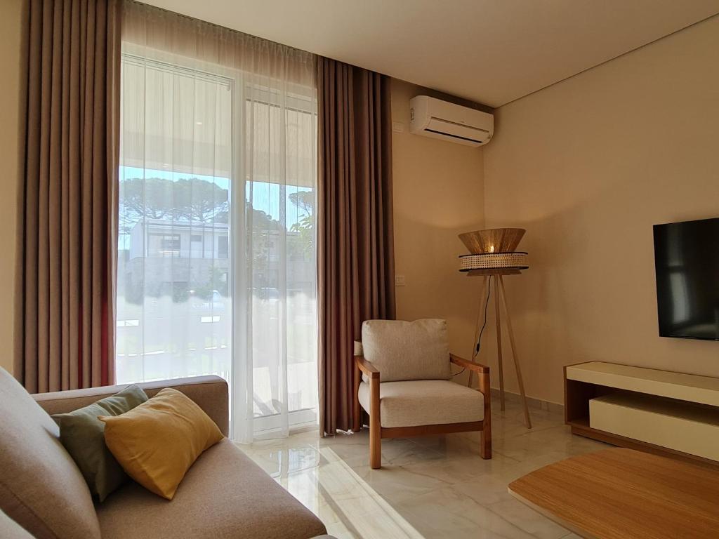 - un salon avec un canapé, une chaise et une télévision dans l'établissement Gjiri i Lalzit - San Pietro - Savita Premium Apartments, à Durrës