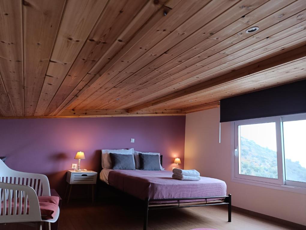 a bedroom with purple walls and a wooden ceiling at Altheas Maisonettes in Xylokastron