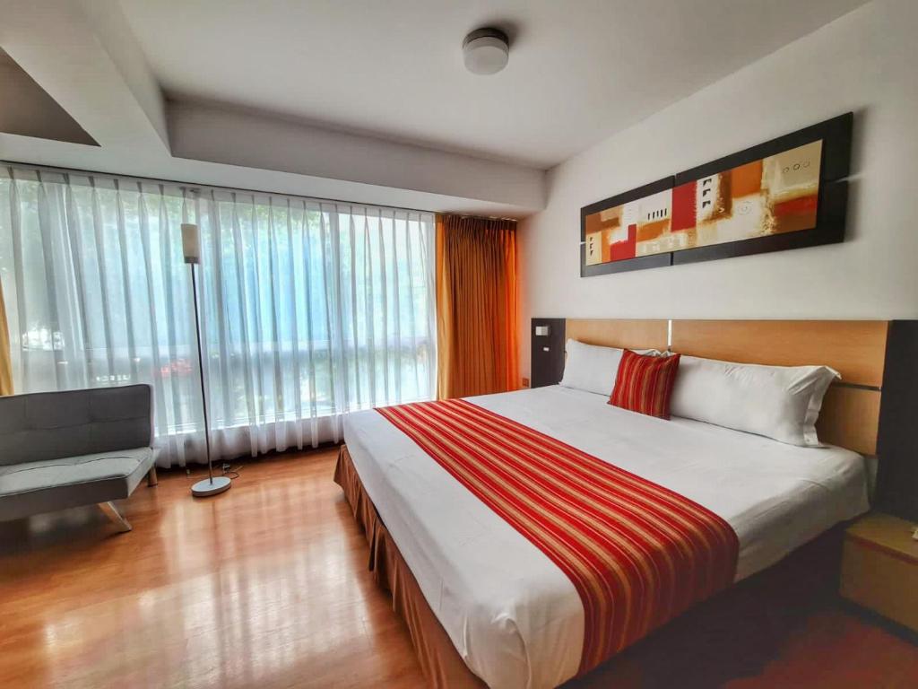 Una habitación de hotel con una cama grande y una silla. en Allpa Hotel & Suites, en Lima