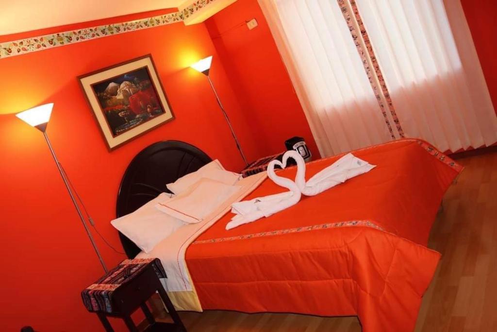 a red bedroom with a bed with a ribbon on it at Colca Andina Inn Chivay in Chivay