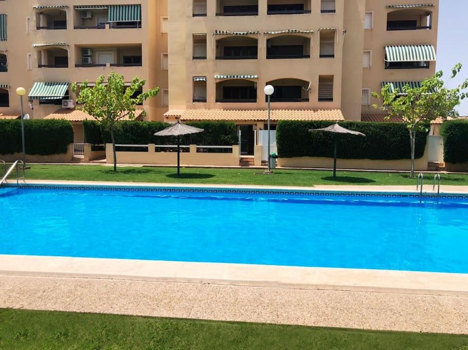a large blue swimming pool in front of a building at 3 bed ground first floor apartment. Close to beach in Mar de Cristal