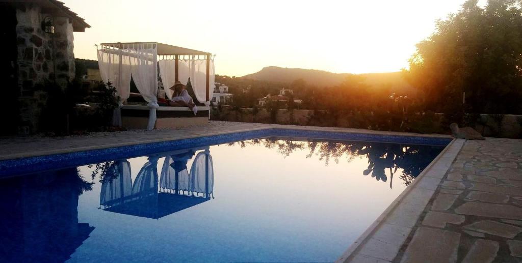 a woman sitting on a bench next to a swimming pool at Simona Stone House in Polis Chrysochous