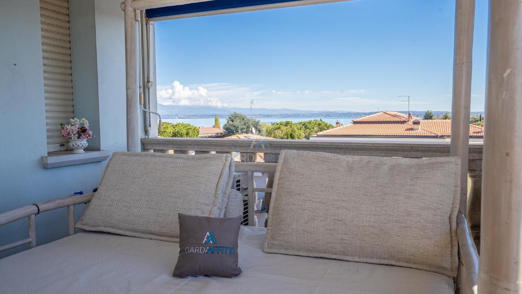 een veranda met een bed en kussens op een balkon bij Palladium Apt -Attico Vista Lago in centro Colombare, Sirmione in Sirmione